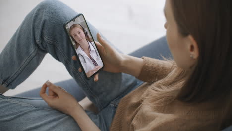 Woman-using-medical-app-on-smartphone-consulting-with-doctor-via-video-conference.-Female-using-online-chat-to-talk-with-family-therapist-and-checks-possible-symptoms-during-pandemic-of-coronavirus.